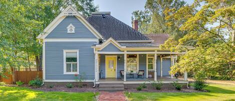 A two-story house with a front porch, a brick pathway leading to the entrance, and a well-maintained lawn.