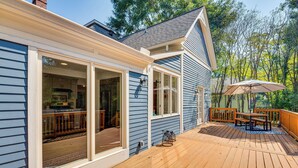 A deck with a wooden table and chairs, a large umbrella, and a view of the backyard. - Walk to Mcdonough Square: Historic Home w/ Yard! (McDonough)