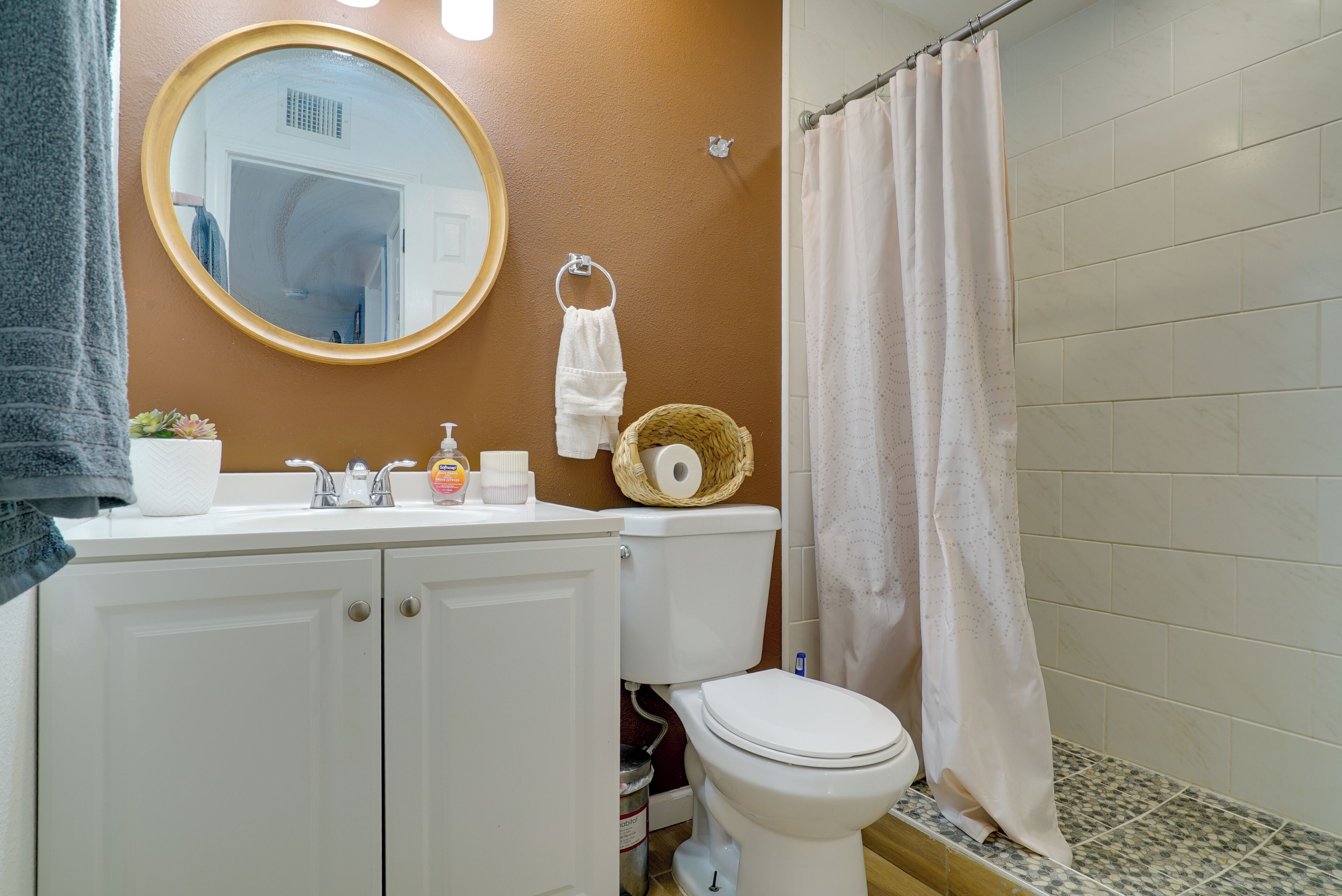 A bathroom with a white sink, a toilet, a mirror, and a shower curtain.