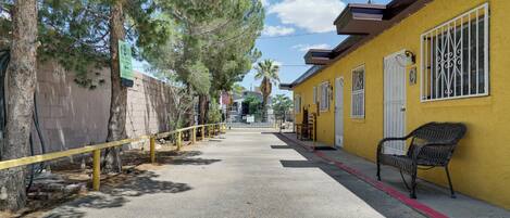 A street with a yellow building, a bench, and trees.