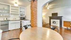 A modern kitchen with white cabinetry, a brick column, a dining table, and a fireplace.