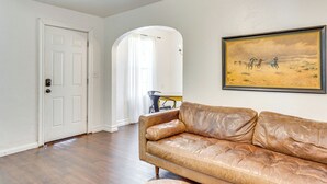 A living room with a leather sofa, a door, and a painting on the wall.