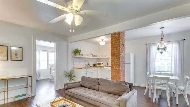 A modern living room with a sofa, a dining table with chairs, a kitchen area, and a ceiling fan. - Heart of OKC Plaza District: Duplex Near Shops! (Oklahoma City)