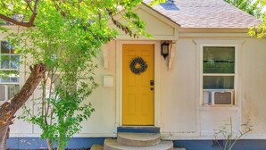 A yellow front door with a wreath, a small porch with steps, and a window with blinds. - Heart of OKC Plaza District: Duplex Near Shops! (Oklahoma City)