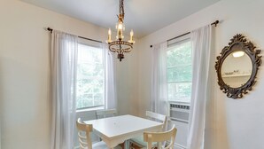 A dining area with a white table and chairs, a chandelier, and a mirror on the wall. - Heart of OKC Plaza District: Duplex Near Shops! (Oklahoma City)