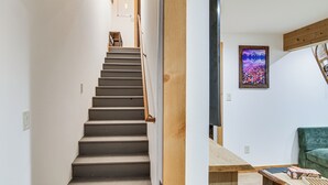 A staircase leading to a room with a wooden table, a framed picture on the wall, and a green chair. - Sauna, Gas Grill & More! Belgrade Duplex (Belgrade)