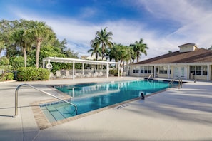 A swimming pool with a sun deck, lounge chairs, and palm trees. - Walk to Beach: 1st-floor Unit w/ Pool in Melbourne (Indialantic)