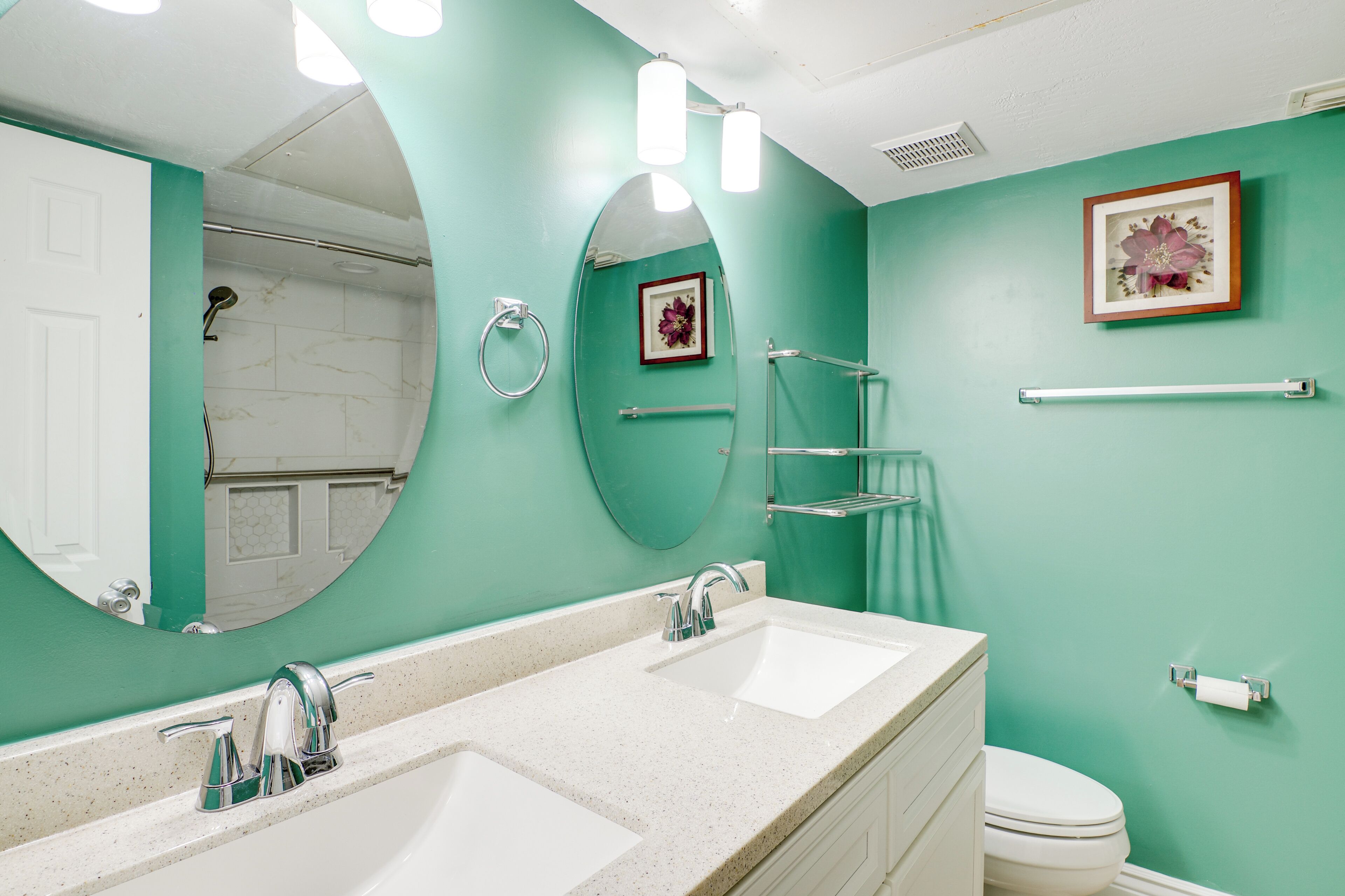 A bathroom with two sinks, a toilet, a shower, and a mirror.