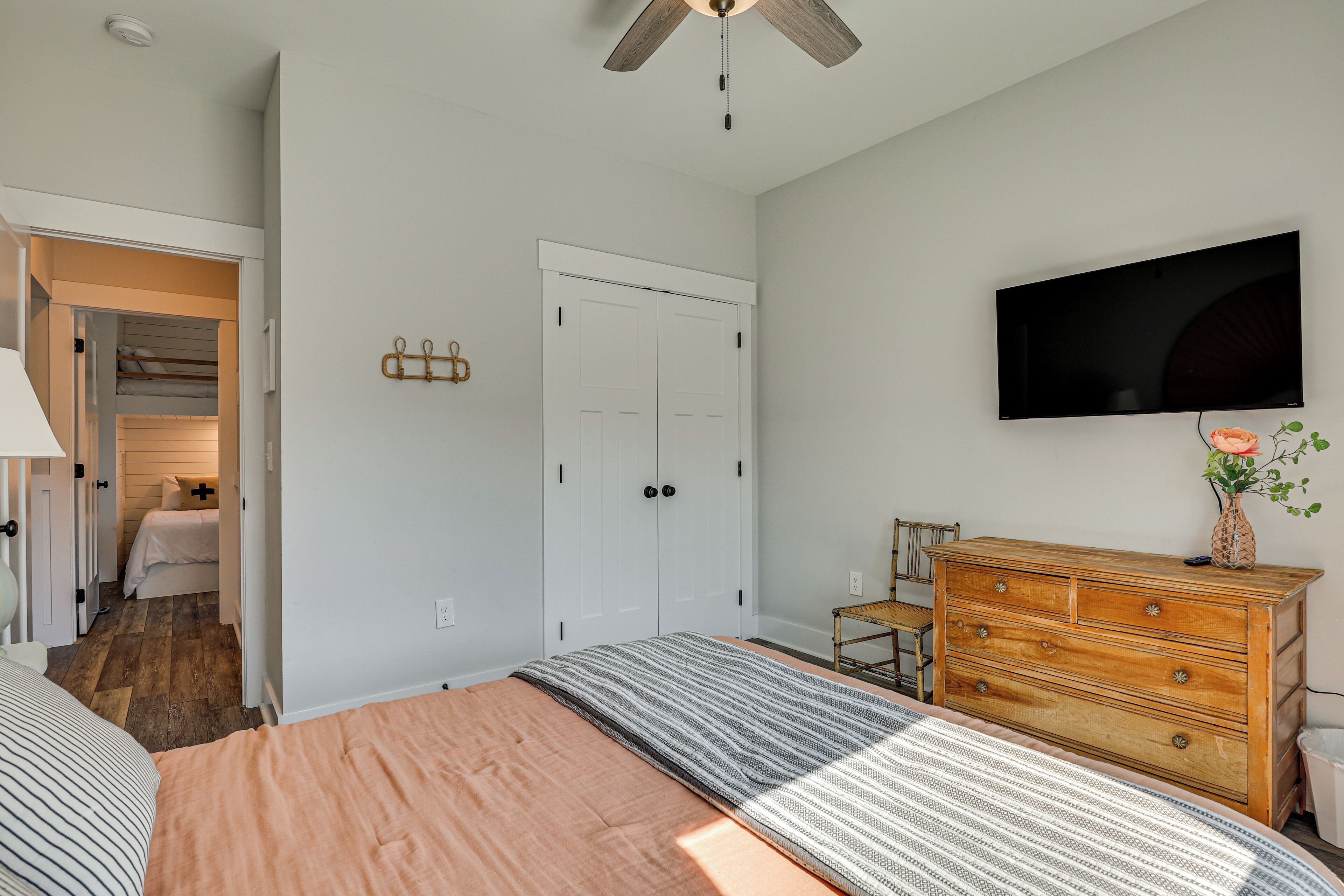 A bedroom with a bed, a dresser, a television, and a closet.