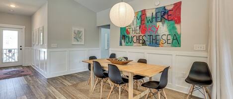 A dining area with a wooden table, black chairs, and a colorful abstract painting on the wall.