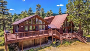 Eine Holzhütte mit Terrasse und Garage, umgeben von Bäumen.