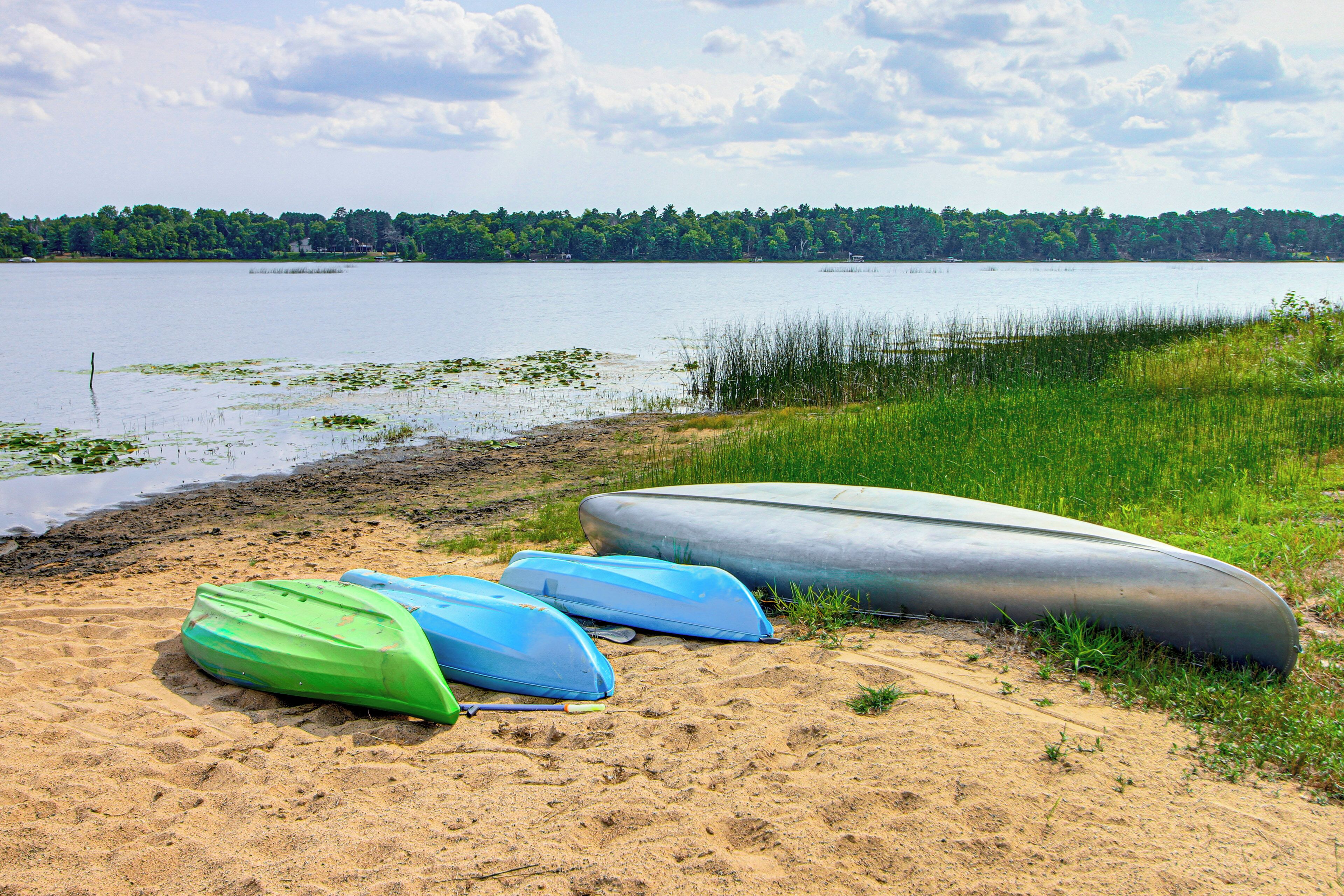 A lakeside view with kayaks and canoes on the shore.