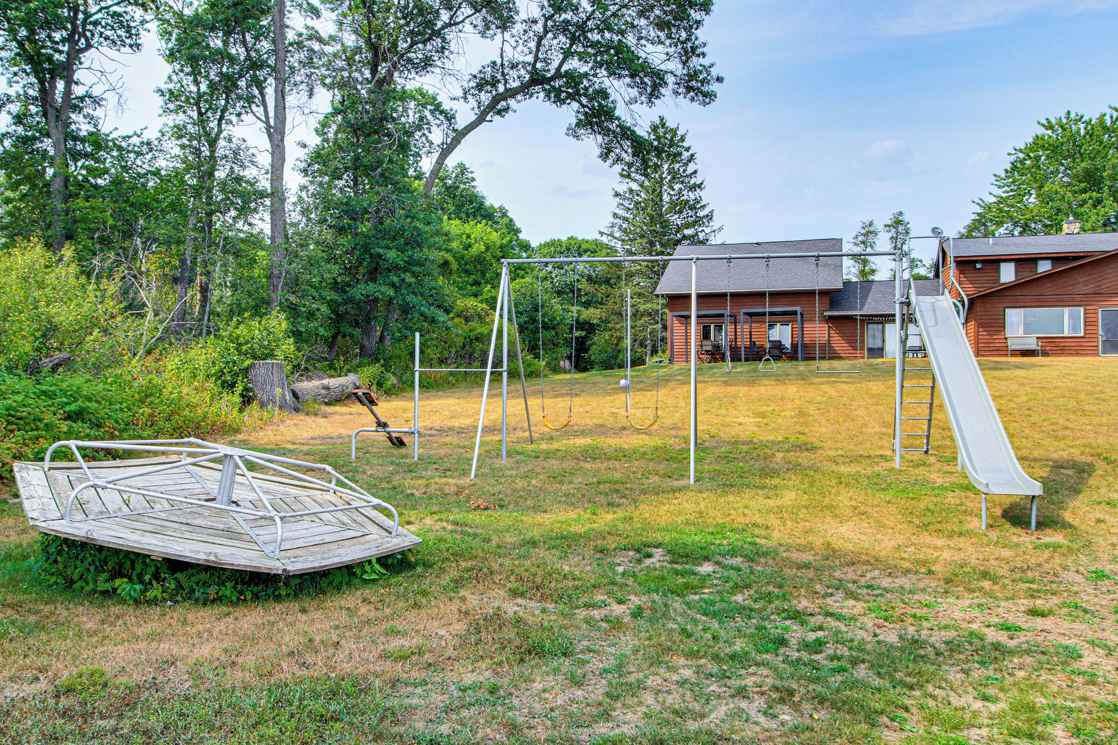 A playground with swings, a slide, and a wooden deck.