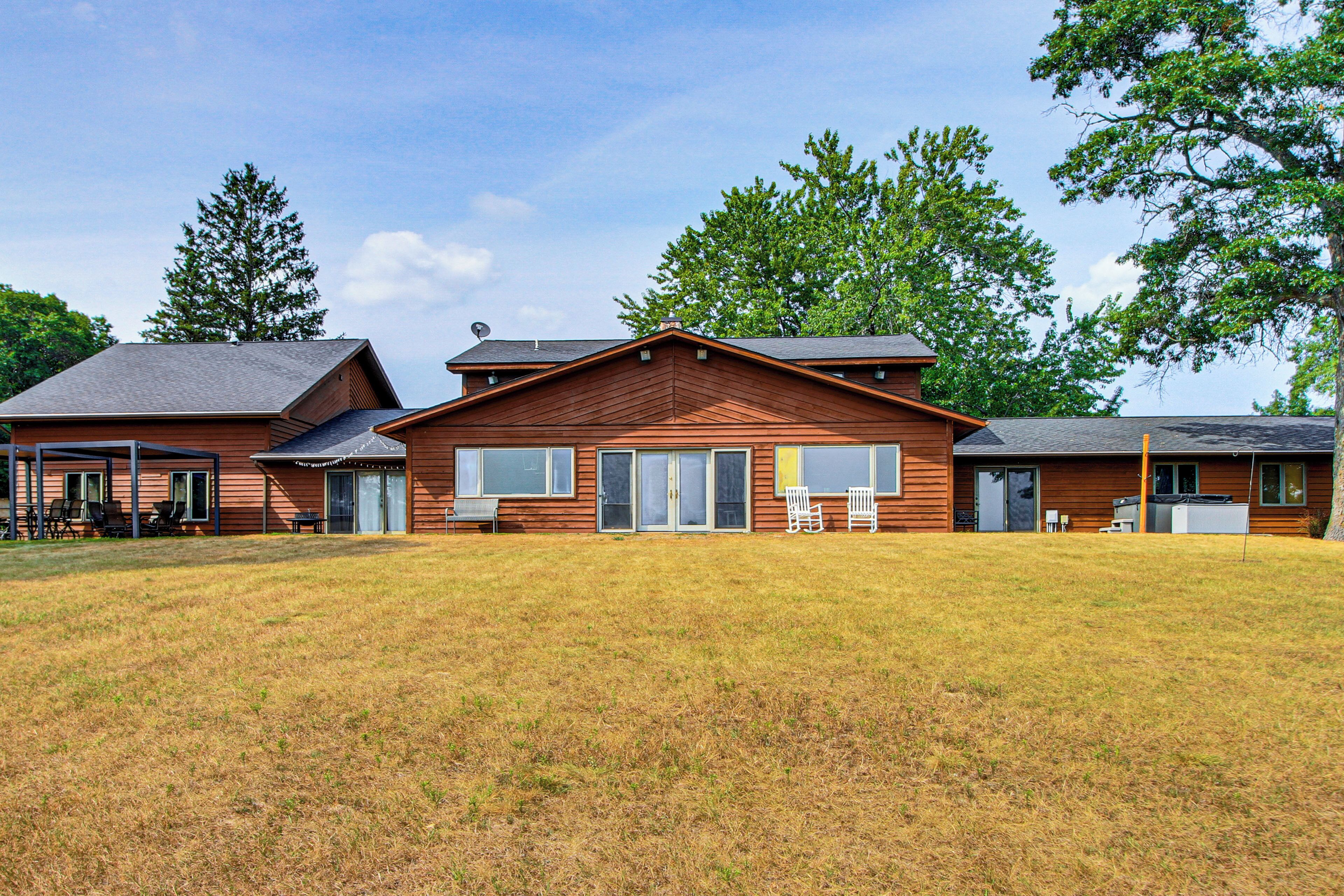 A two-story wooden building with a covered patio area and a grassy lawn in front.