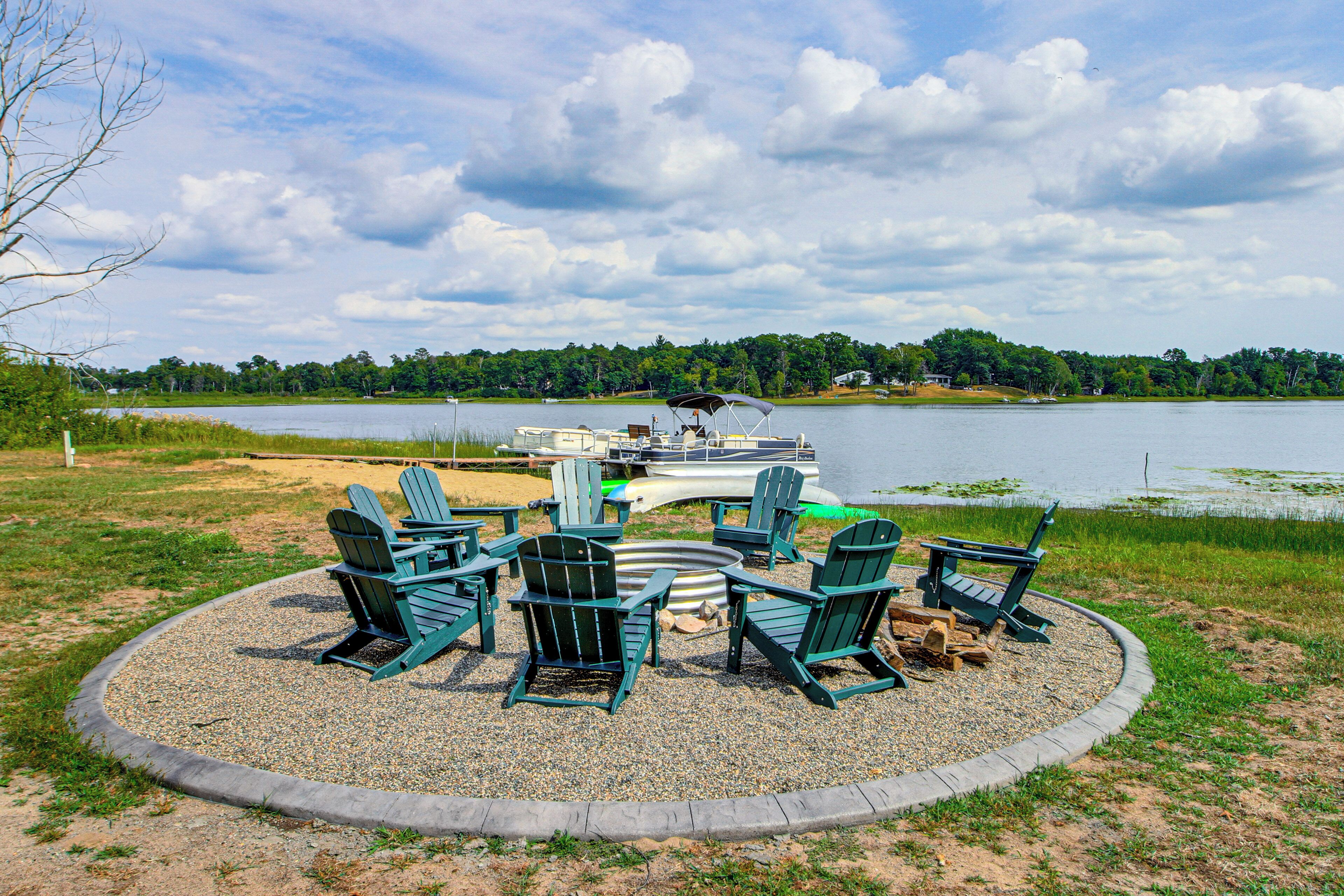 A lakeside seating area with Adirondack chairs and a boat docked in the background.