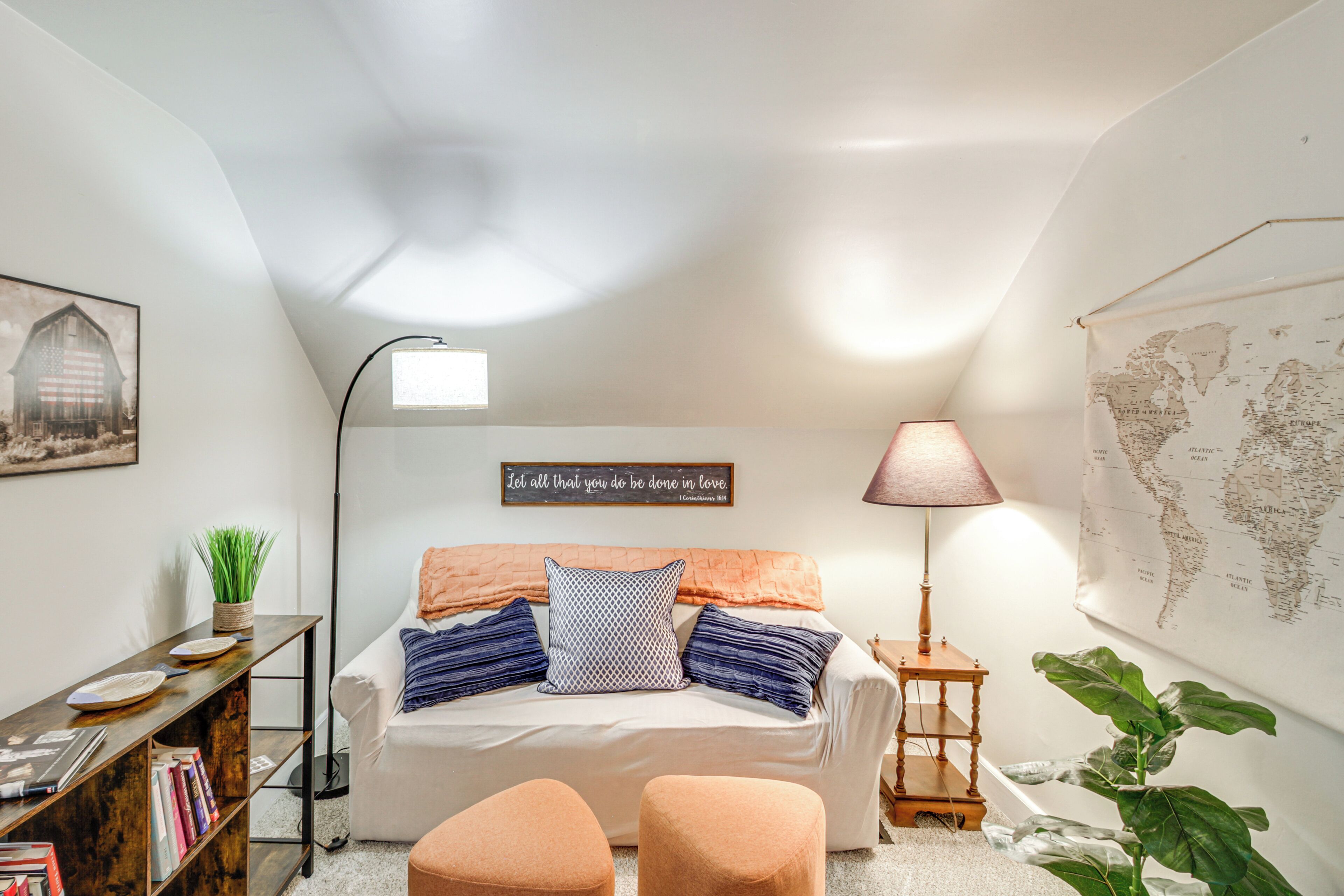 Une chambre confortable avec un lit, une carte du monde, une lampe et une bibliothèque.