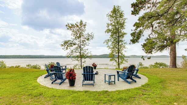 Ein Sitzbereich am Seeufer mit Adirondack-Stühlen und einem Feuerkorb aus Beton.