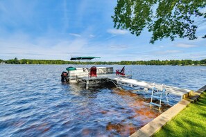 A boat docked at a pier with a covered seating area and a ladder.
