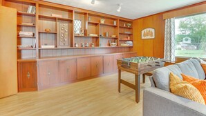 Una habitación amplia con paneles de madera, una mesa de fútbol de mesa y un ventanal con vistas al exterior.