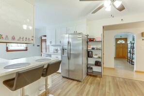 Una cocina moderna con refrigerador de acero inoxidable, gabinetes de madera y un comedor con taburetes de bar.