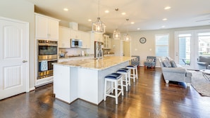 A spacious kitchen with white cabinetry, stainless steel appliances, and a central island with bar stools. - Spacious Townhome 2 Mi to Bethany Beach Boardwalk (Frankford)