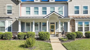 A two-story residential building with a front porch, a stone accent wall, and a small garden with trimmed bushes. - Spacious Townhome 2 Mi to Bethany Beach Boardwalk (Frankford)