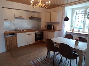 A modern kitchen with wooden cabinets, a built-in oven, and a dining area with a table and chairs.