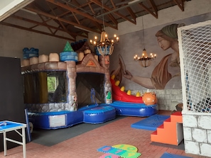 Ein Spielbereich mit Trampolin, Hüpfburg und Wandgemälde.