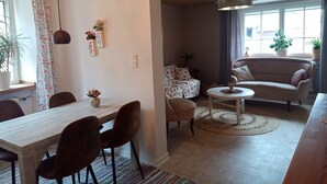 A dining area with a table and chairs, a sofa, a small round table, and a potted plant. - Apartment 'Child-Friendly at the Village Shop' with Private Terrace and Wi-Fi (Blankenheim)