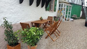 An outdoor seating area with a wooden table and chairs, surrounded by potted plants. - Apartment 'Child-Friendly at the Village Shop' with Private Terrace and Wi-Fi (Blankenheim)