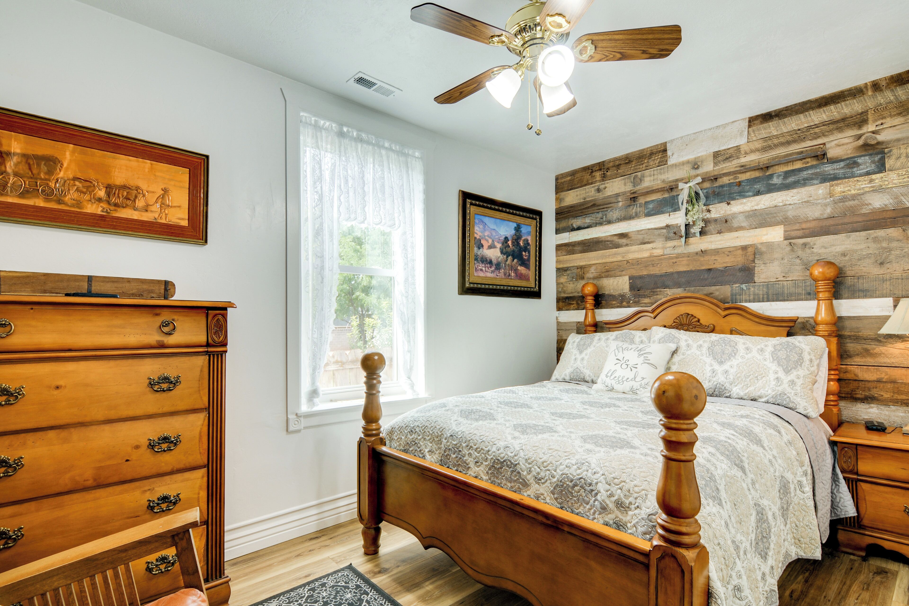 A bedroom with a wooden bed, a dresser, and a ceiling fan.