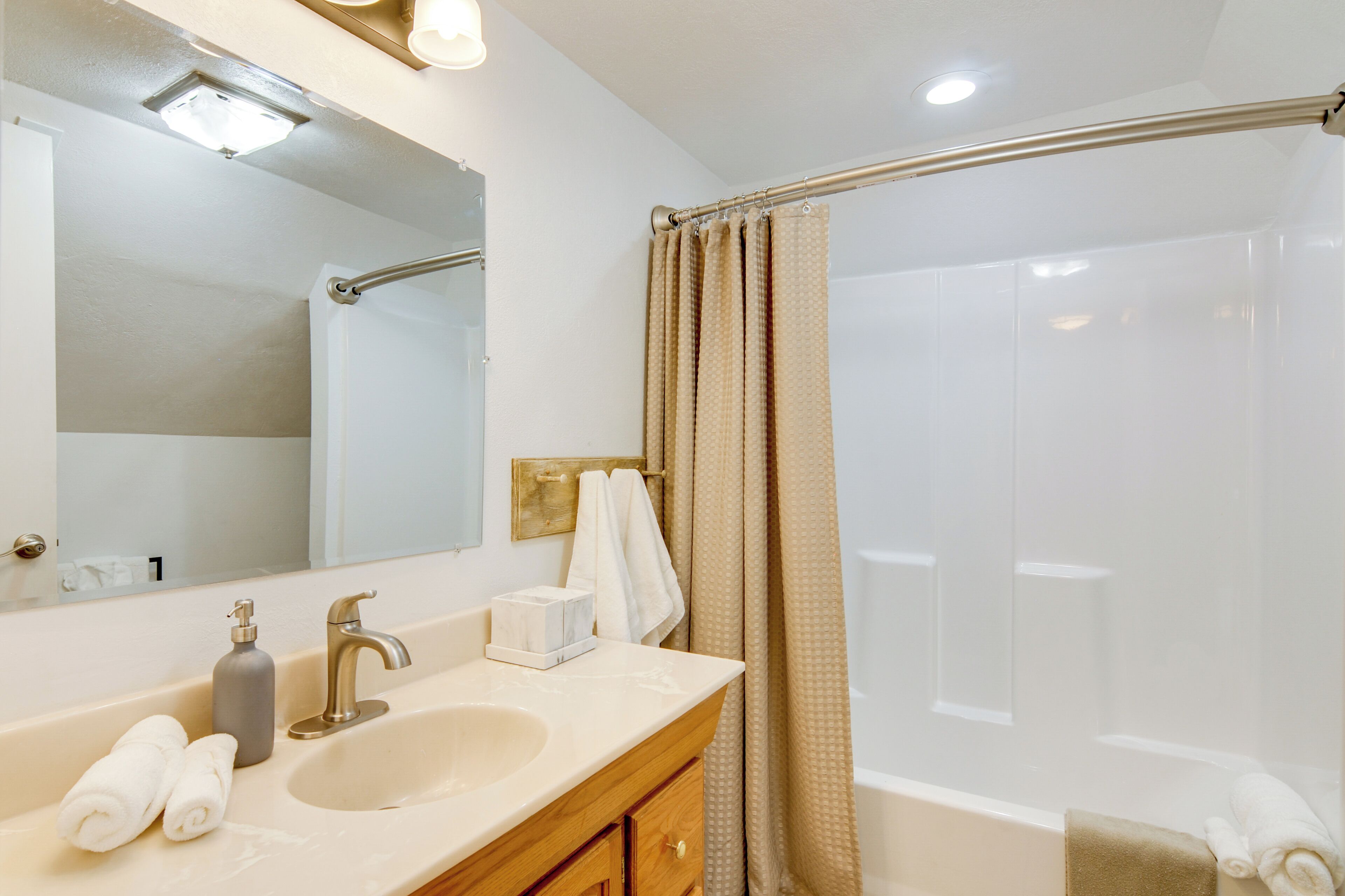 A bathroom with a sink, mirror, towel rack, and shower curtain.