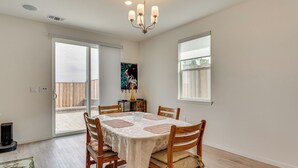 A dining area with a table set for four, wooden chairs, a chandelier, and a painting on the wall.