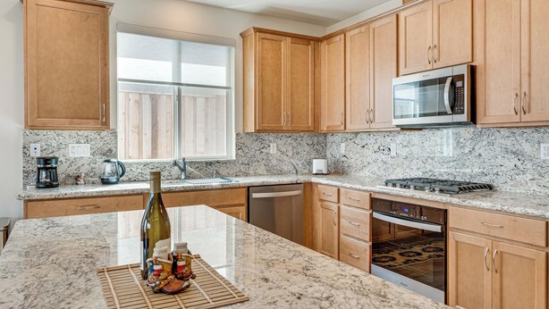 A kitchen with wooden cabinets, a microwave, a stove, and a dishwasher.