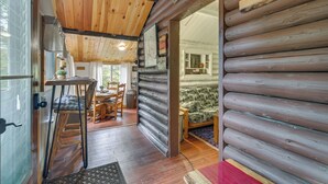 A log cabin interior with a dining area, a sofa, and a wooden ceiling. - Deck + Fire Pit: Nature Lover's Retreat in Maine! (Errol)