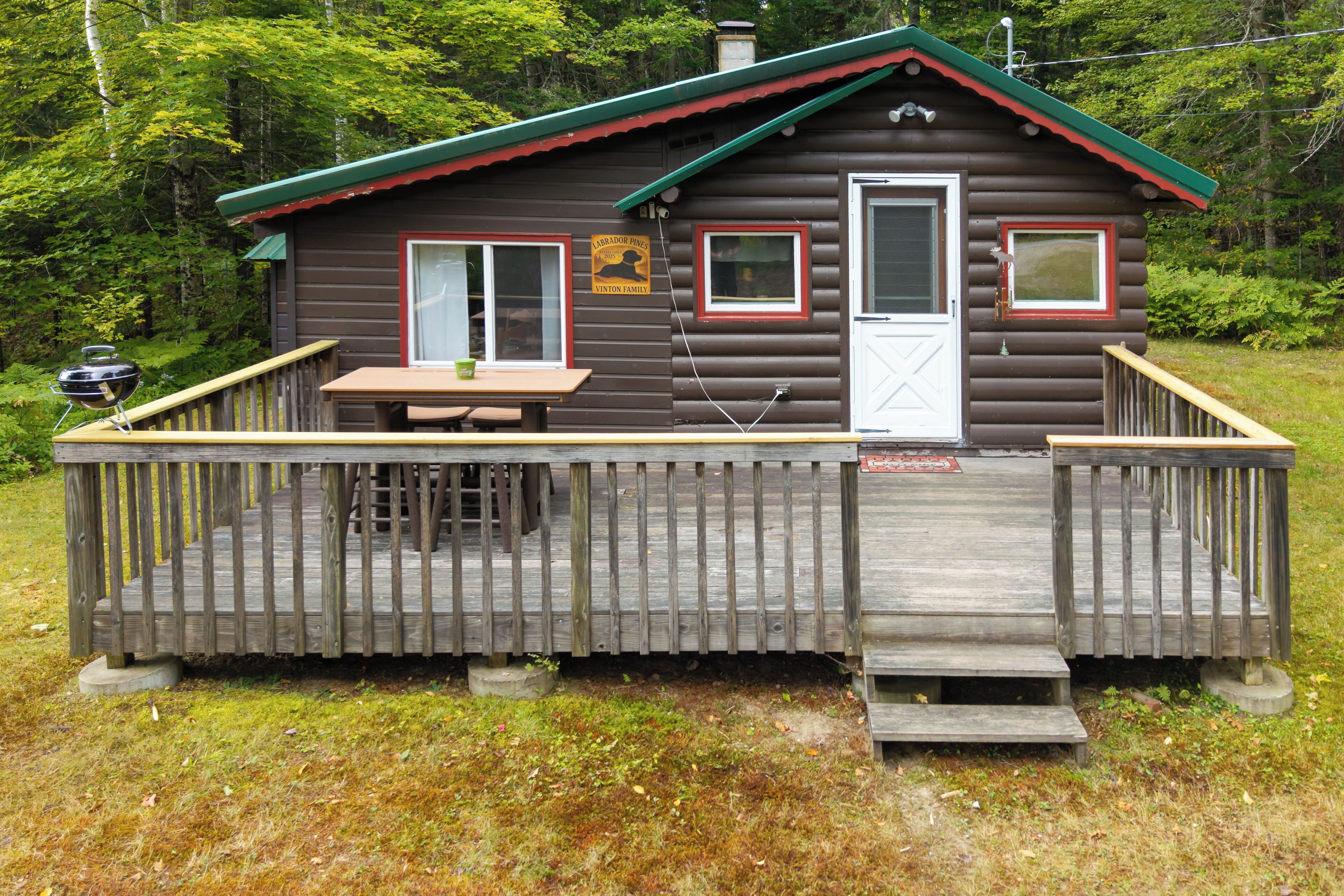 A cabin with a deck, a table, and a grill.