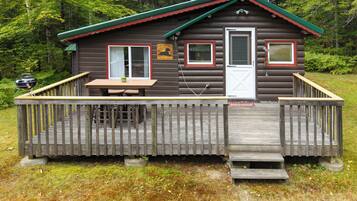 A cabin with a deck, a table, and a grill.