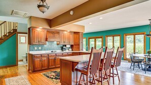 A spacious kitchen with wooden cabinets, a large island, and a dining area with chairs and a table. - Rural & Private Dover Retreat: Close to Wineries! (Dover)