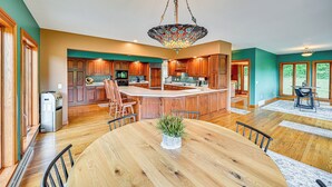 A spacious kitchen with wooden cabinets, a central island, and a dining area with a wooden table and chairs. - Rural & Private Dover Retreat: Close to Wineries! (Dover)
