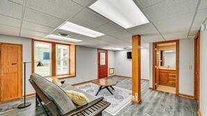 A spacious room with a large window, a wooden bench, a patterned rug, and a door leading to another room. - Rural & Private Dover Retreat: Close to Wineries! (Dover)