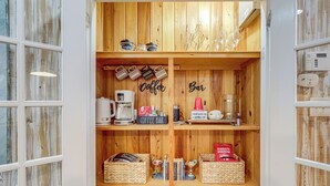 A wooden interior with a coffee bar area, including coffee machines, mugs, and a sign that reads "Coffee Bar."