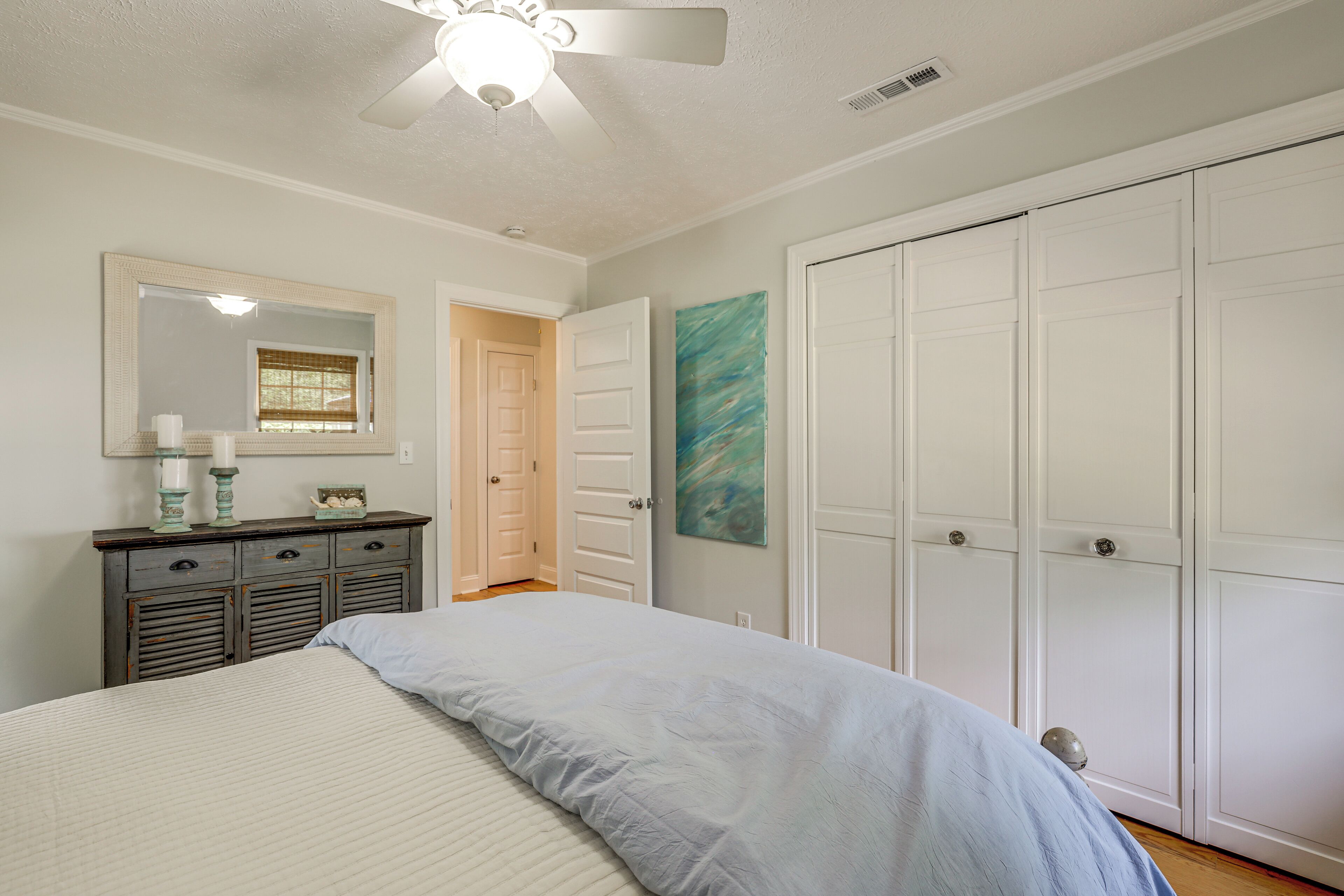 A bedroom with a bed, dresser, mirror, and wardrobe.
