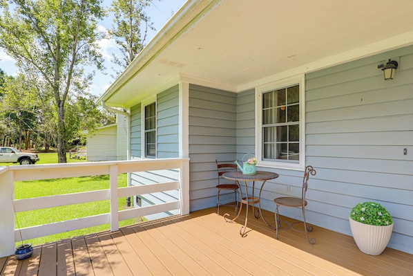 A porch with a table and chairs, a potted plant, and a view of a grassy yard. - 3 Mi to Beach: Pawleys Island Cottage (Pawleys Island)
