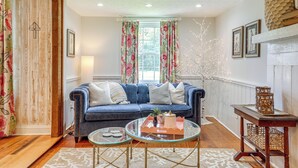 A living room with a blue sofa, a glass coffee table, and a fireplace.