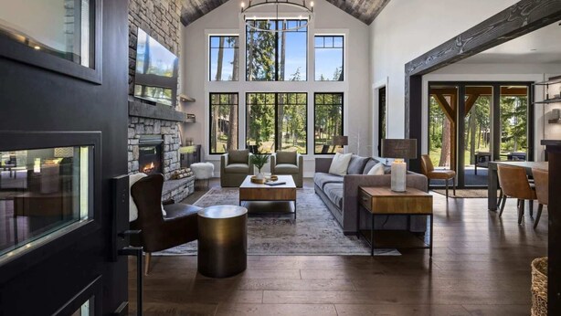 A spacious living room with a stone fireplace, large windows, and a high ceiling with exposed beams. - FairwayView, HotTub, Firepit, Chef Kit, GameRm, EV (Cle Elum)