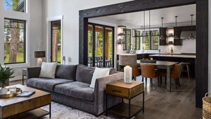 A modern living room with a grey sofa, wooden coffee table, and a dining area with a wooden table and chairs. - FairwayView, HotTub, Firepit, Chef Kit, GameRm, EV (Cle Elum)