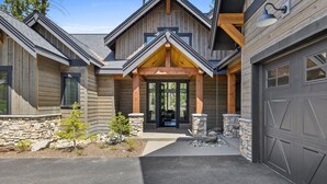 A modern log cabin with a stone foundation, a garage, and a covered entryway. - FairwayView, HotTub, Firepit, Chef Kit, GameRm, EV (Cle Elum)
