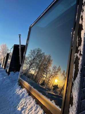 Ein Fenster mit Blick auf Bäume und einen untergehenden Sonnenuntergang.