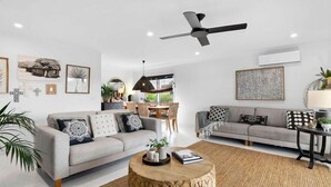 A modern living room with two sofas, a coffee table, and a ceiling fan. - Rye Coastal Haven : 3  BR, 2  BA House in Rye, Sleeps 6 (Rye)