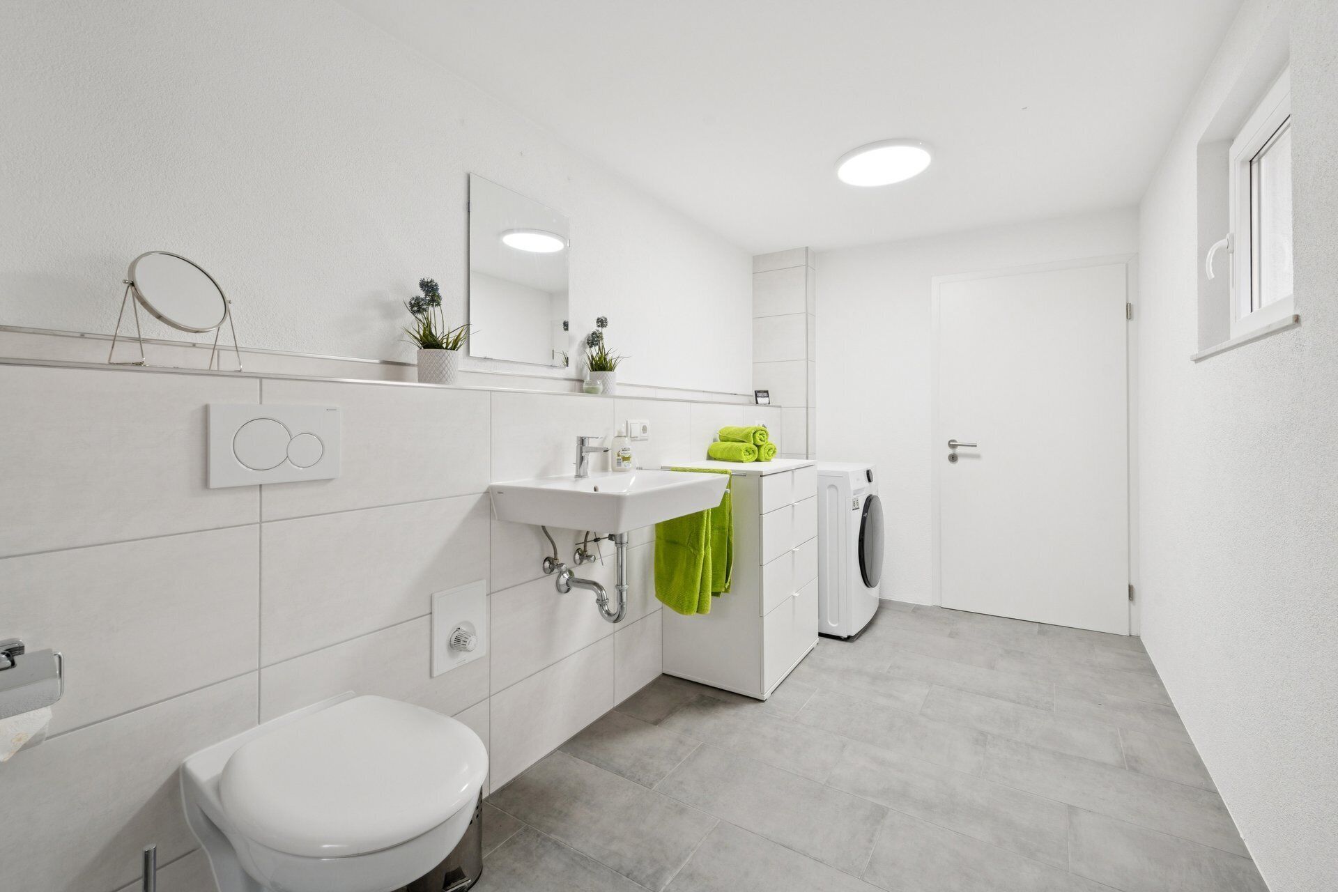 A modern bathroom with a toilet, sink, and mirror.